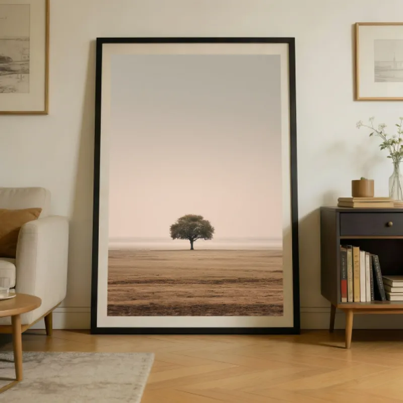 A lone tree standing in a vast open field beneath a soft, hazy beige sky.